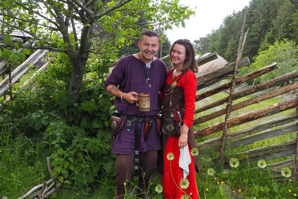 En vikingkvinne og mann foran gjerde på Vikinggarden - Klikk for stort bilde